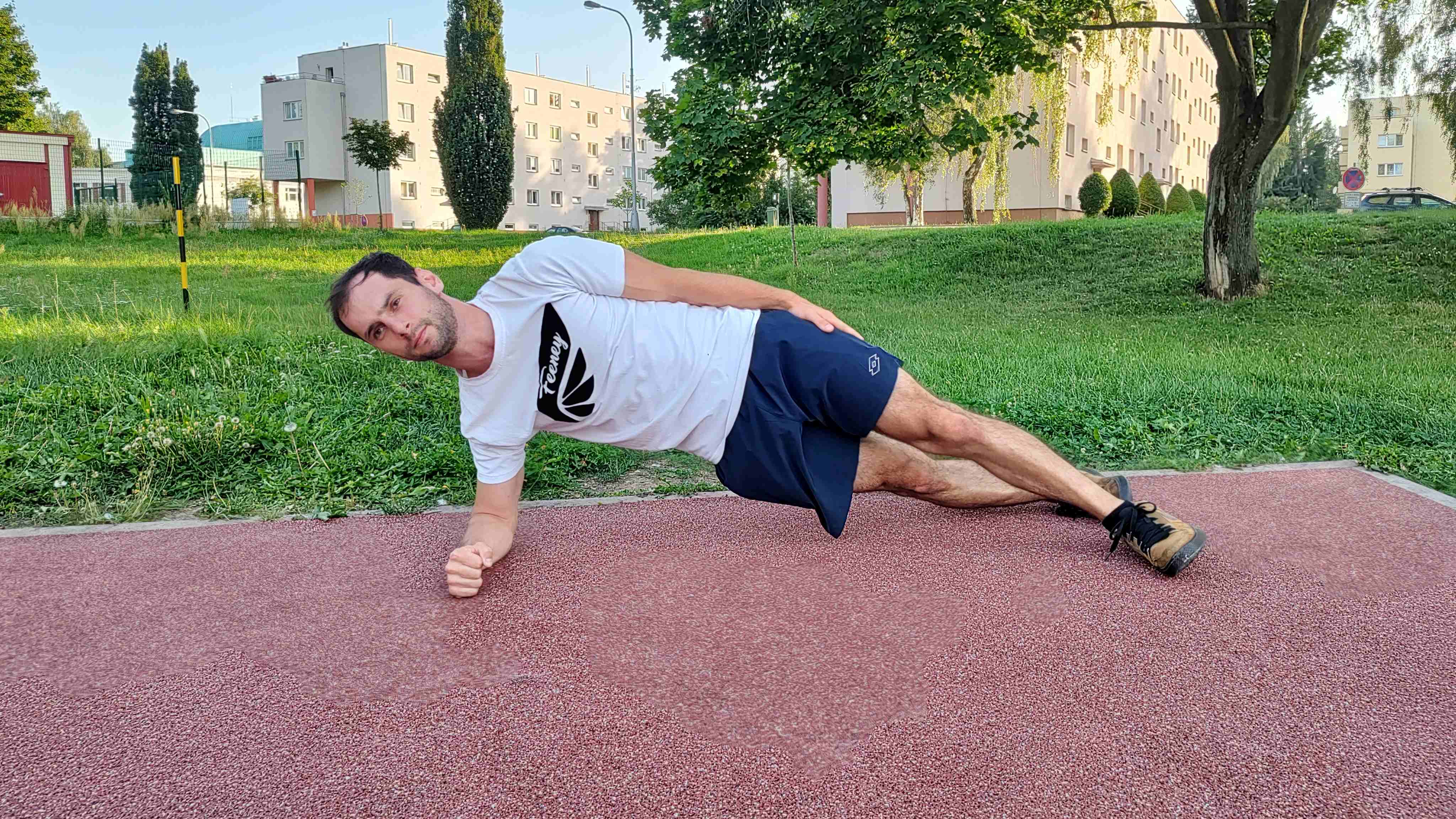 Muž cvičí plank na boku v parku.